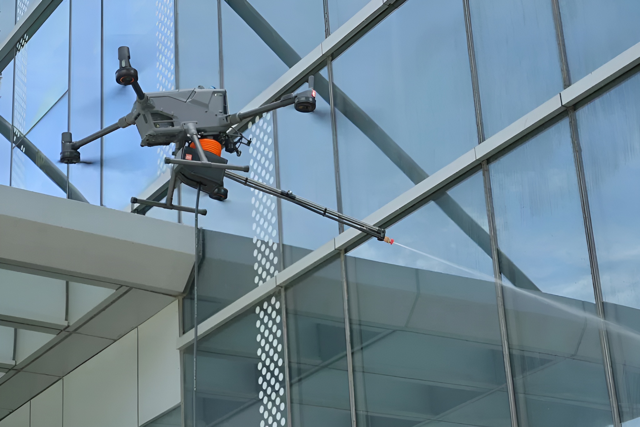 Drönaren DJI Matrice 400 tvättar ett fönster på ett höghus med tvättsystemet Wisson Orion AP3-P3