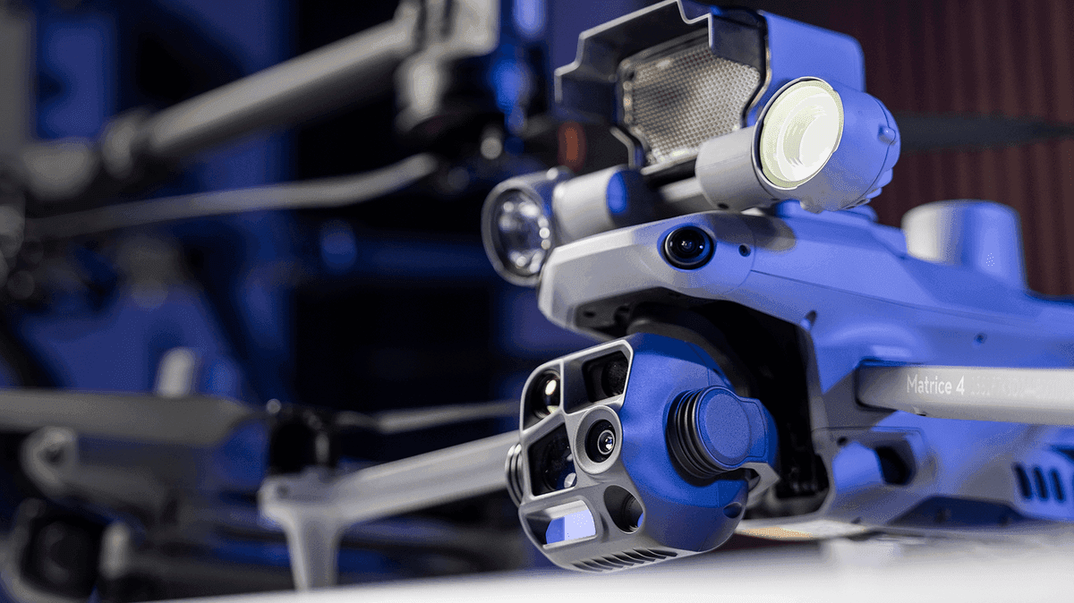 En närbild av en avancerad drönare med flera sensorer och kameror, belyst i ett blått sken.