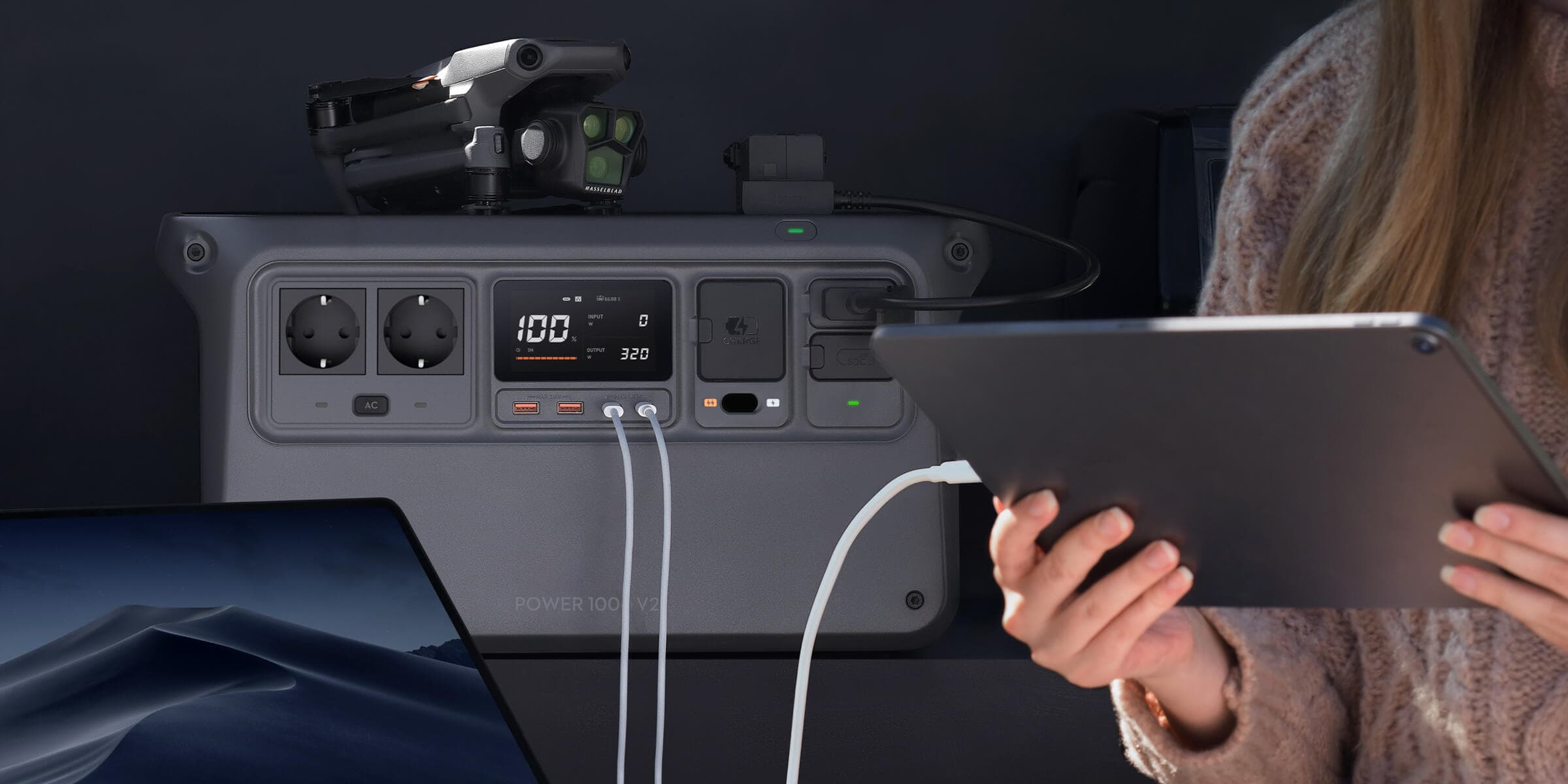 En person använder en surfplatta medan flera enheter laddas från en kraftfull bärbar strömkälla.