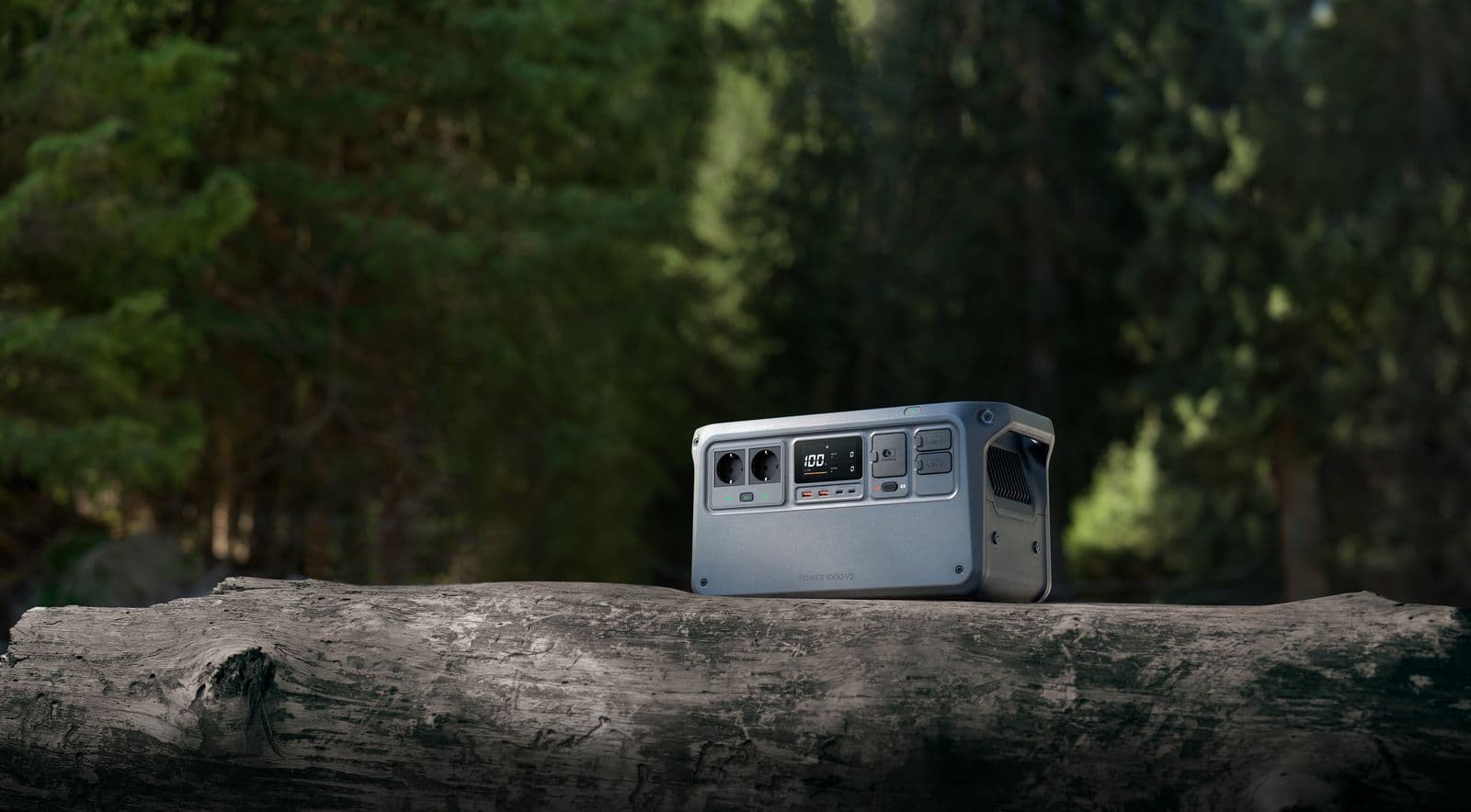 En bärbar DJI Power 1000 V2-kraftstation placerad på en trädstam i en skogsmiljö, redo för utomhusbruk.