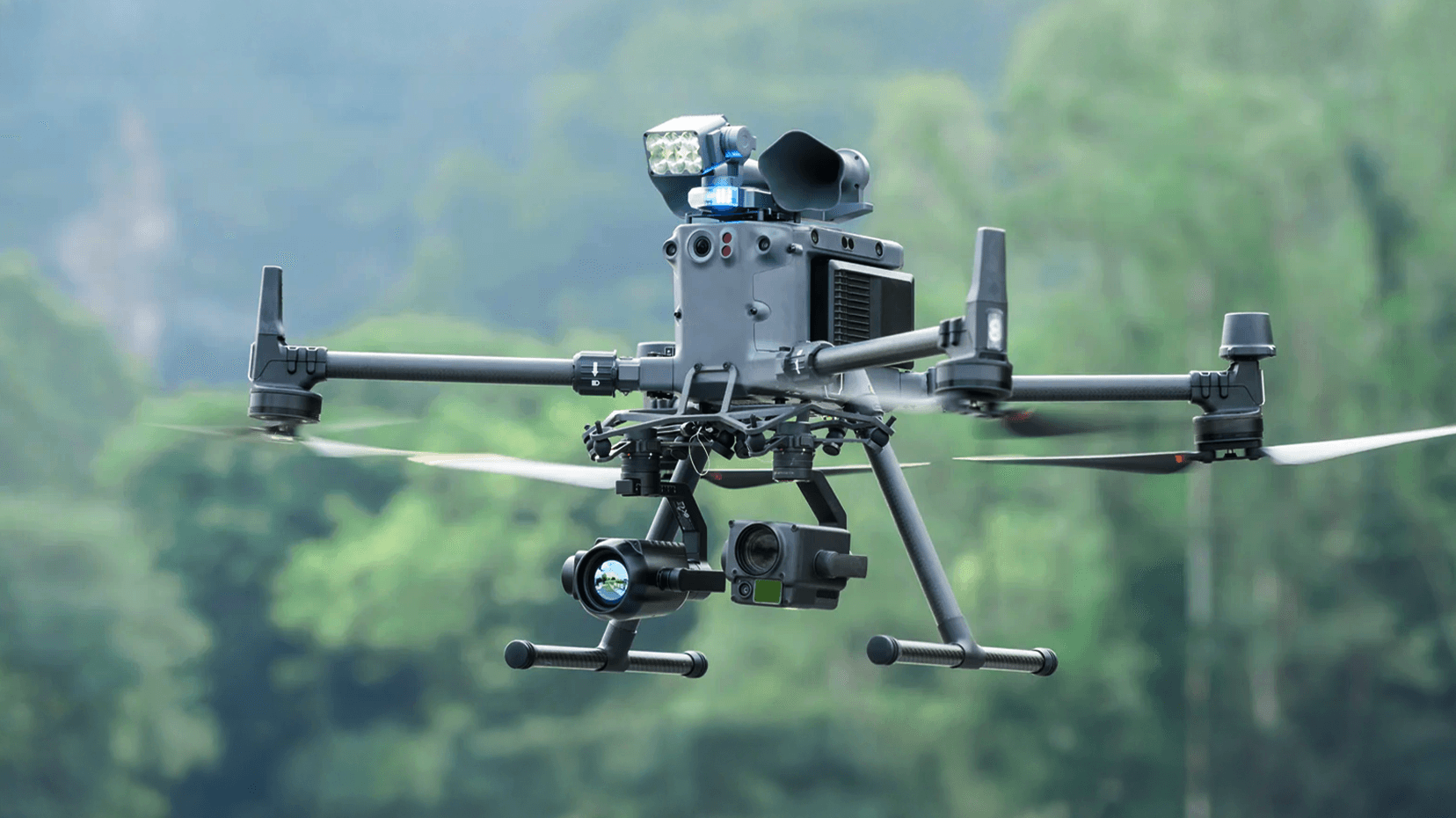 En avancerad drönare svävar i luften med en skog i bakgrunden, utrustad med flera kameror och sensorer.